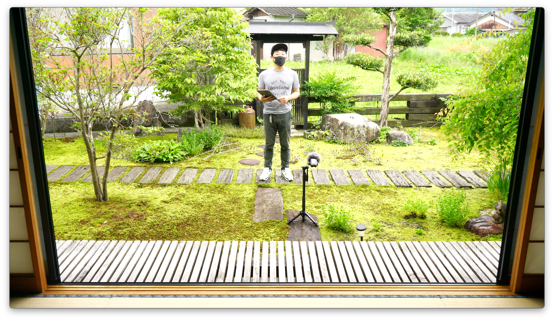 縁側から見た苔庭で、三脚を立てて動画を撮影する西予苔園の代表